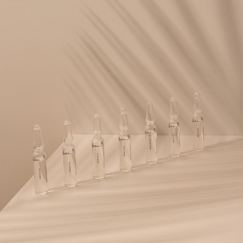 Several ampoules are placed on a table with a pink background