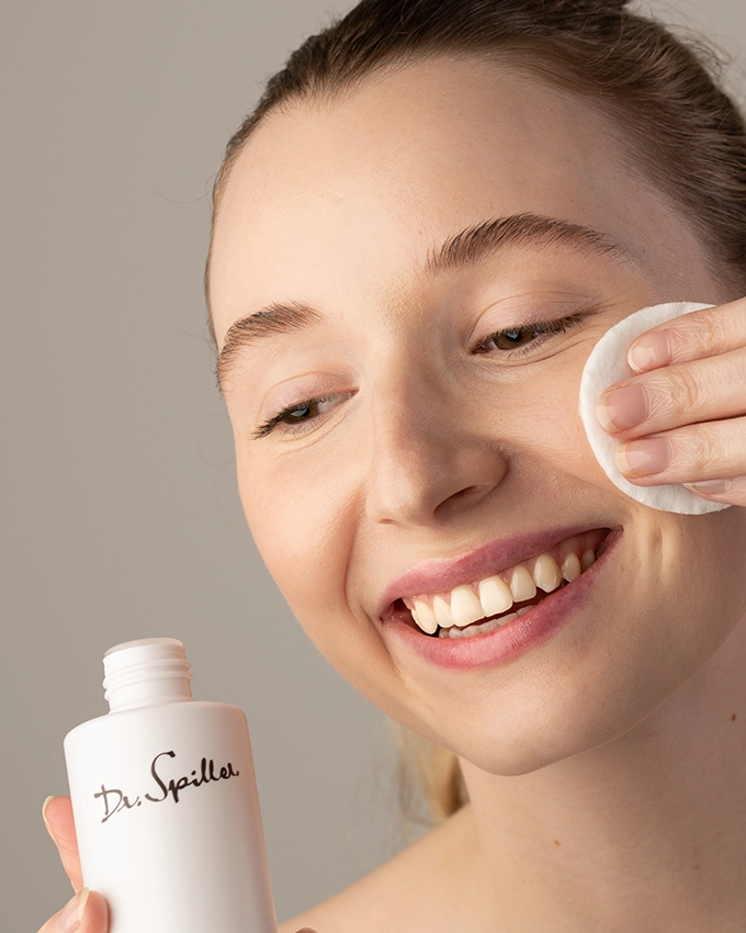 Frau reinigt Gesicht mit Wattepad und Tonic