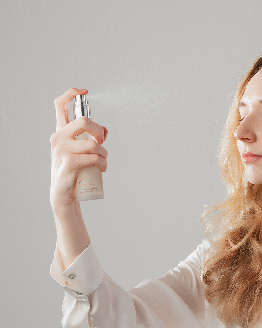 Woman sprays face spray on her face