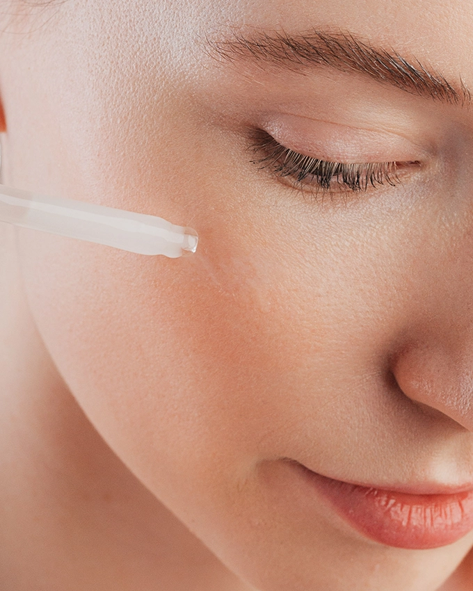 Serum wird mit Pipette auf Wange von Frau aufgetragen