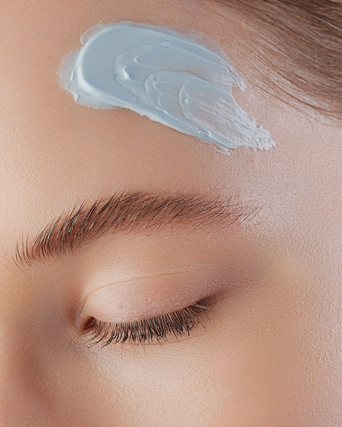 Applying face cream to the forehead with eyes closed