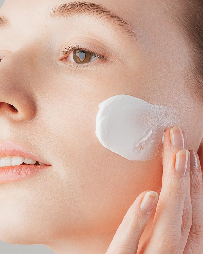 Jojoba Peeling Creme auf Wange von Frau