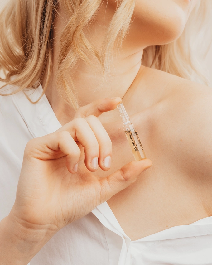 Woman holding a face ampoule with one hand