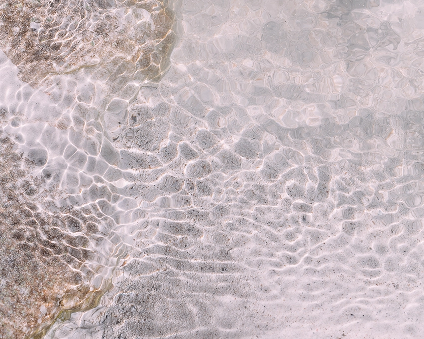 Wasserreflexionen am Sandstrand