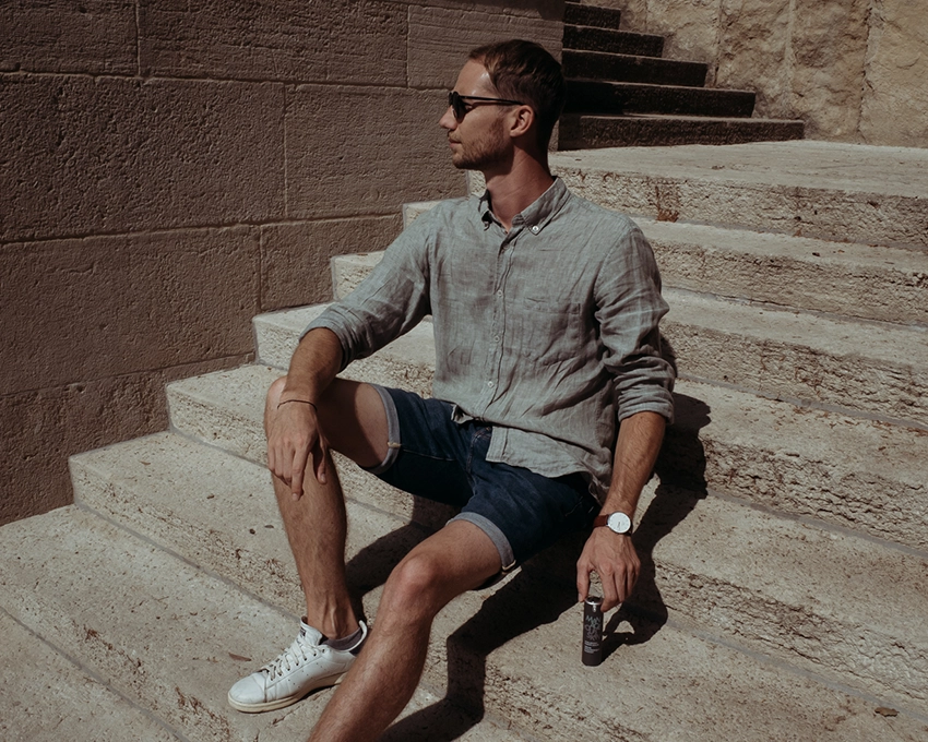 Man posing on a staircase with MY's skincare product in his hand