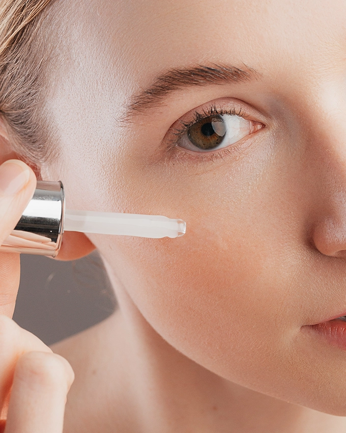 Serum wird mit Pipette auf Wange von Frau aufgetragen