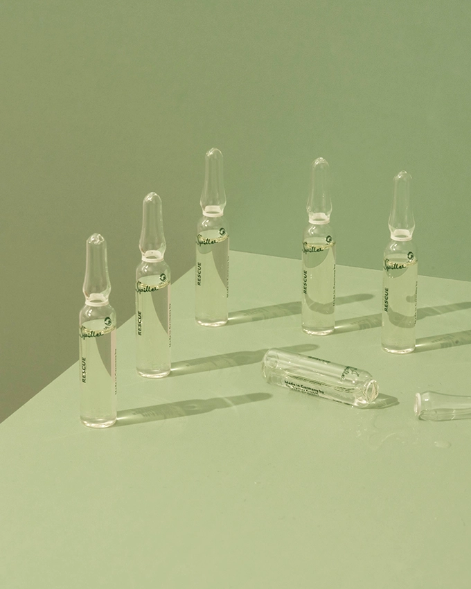 Several ampoules are placed on a table with a green background