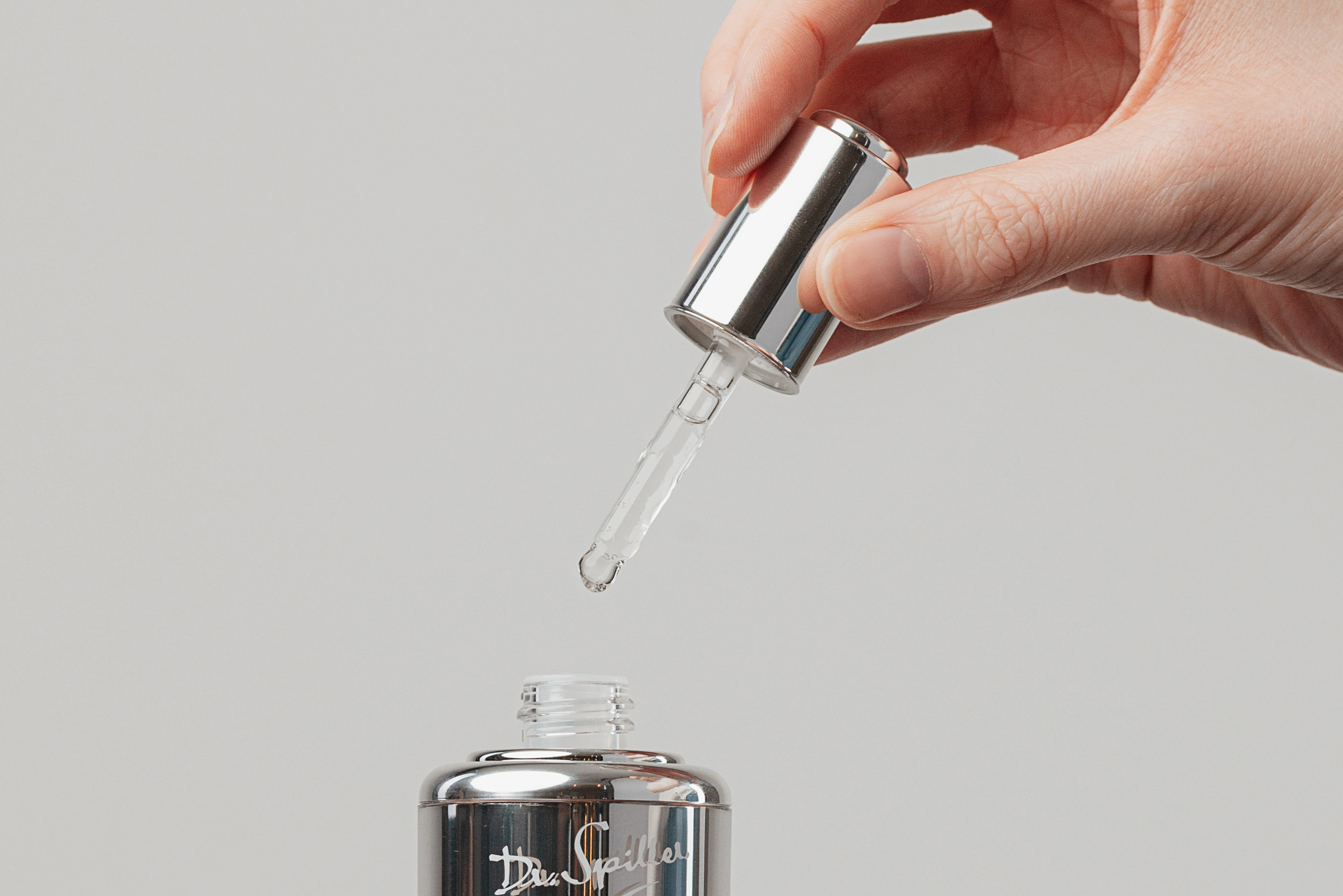 Silver pipette dropper is held by woman